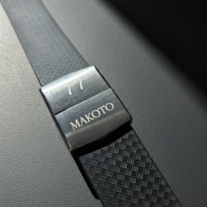 Close-up of a black carbon fiber watch strap with 'Makoto' engraving.