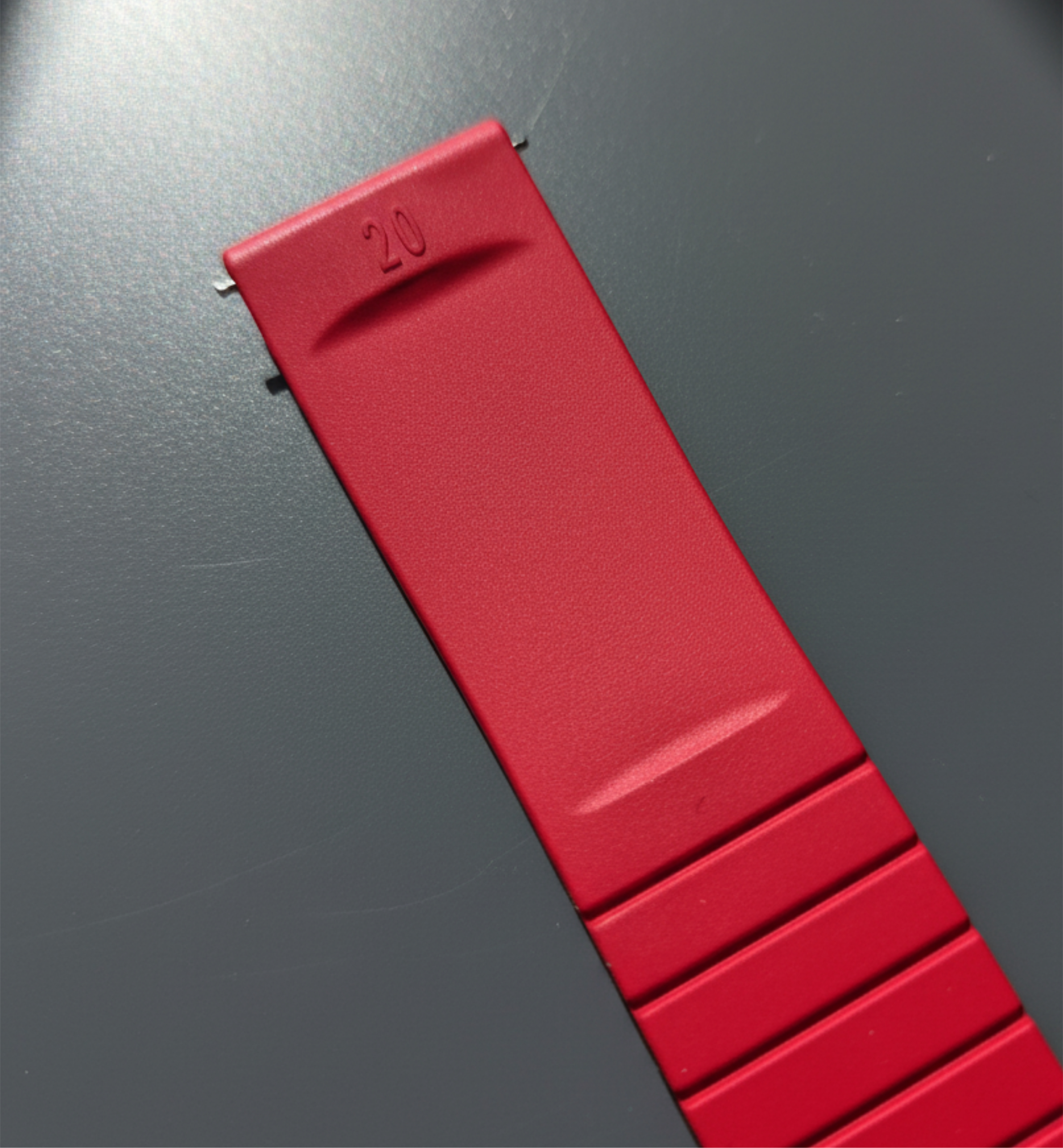 Red silicone watch strap on a dark surface.