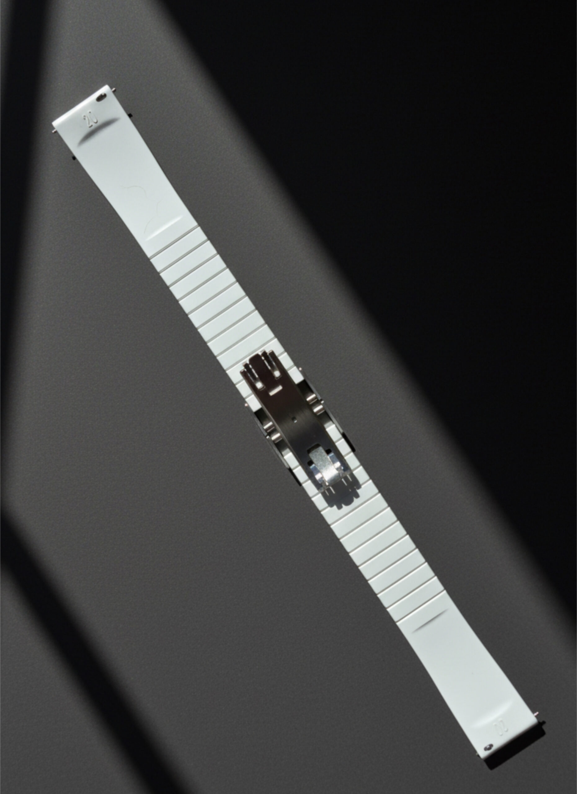 Close-up of a metal latch on a white panel against a dark background.