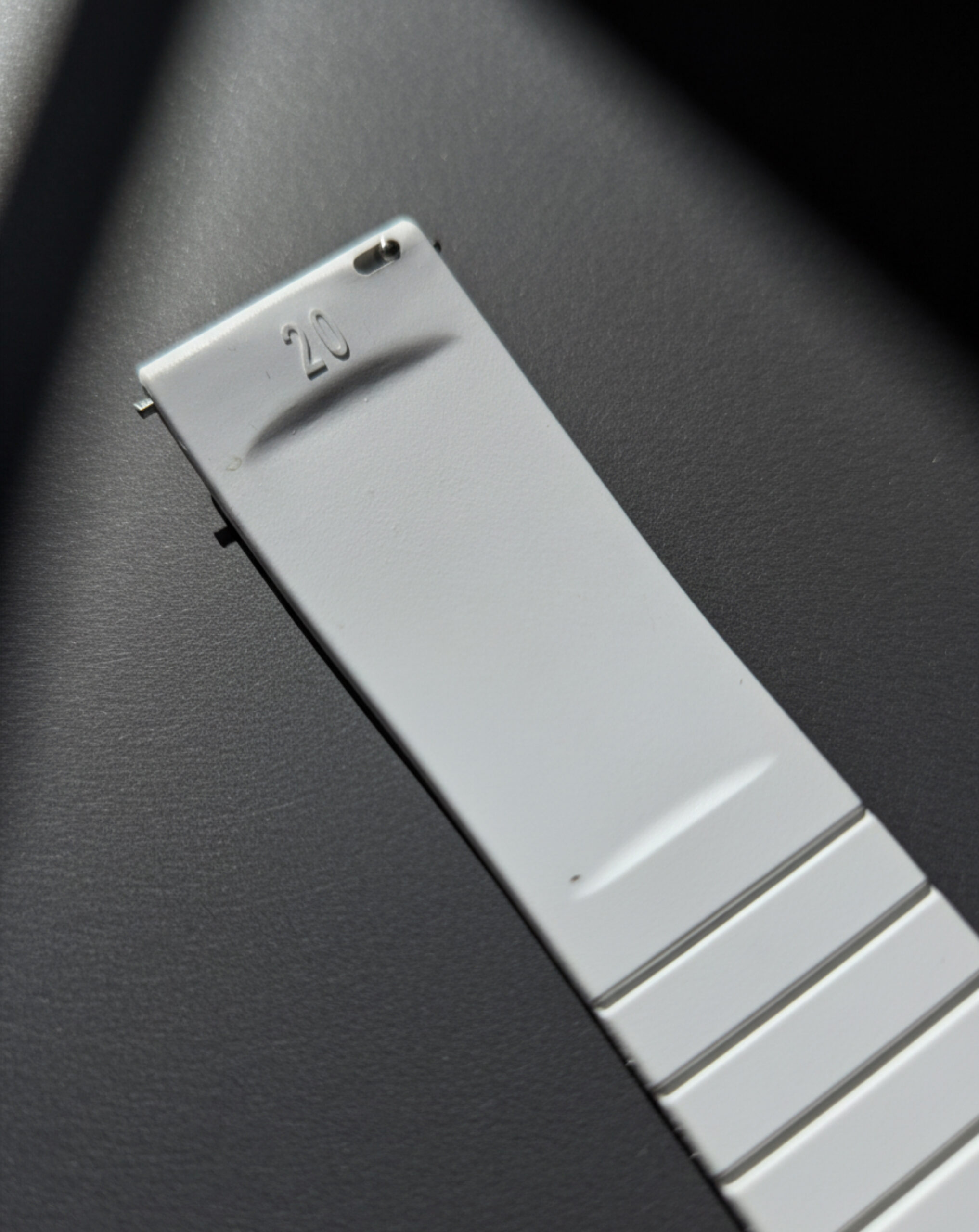 Close-up of a white Apple Watch band on a dark surface.