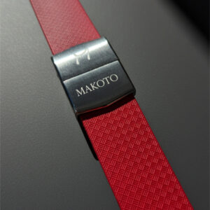 Close-up of a red strap with a metal clasp labeled 'MAKOTO'.